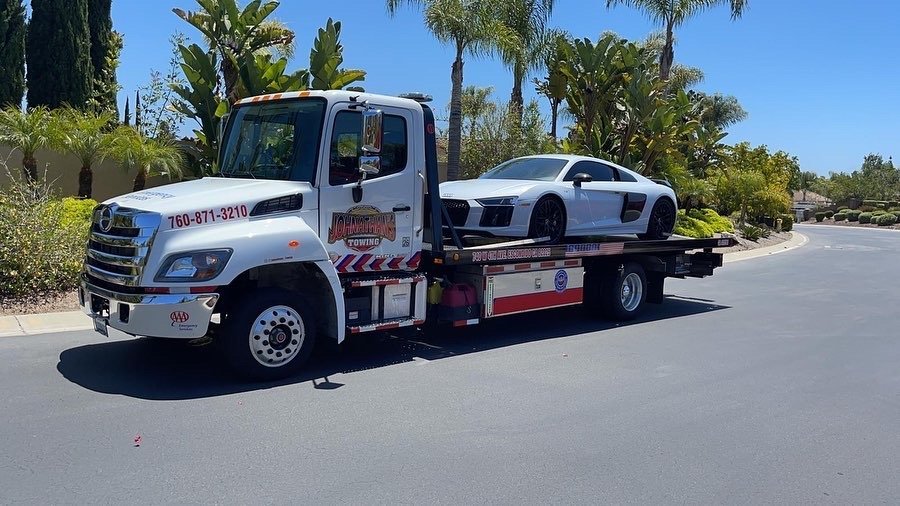 White Audi R8 loaded on a flatbed tow truck