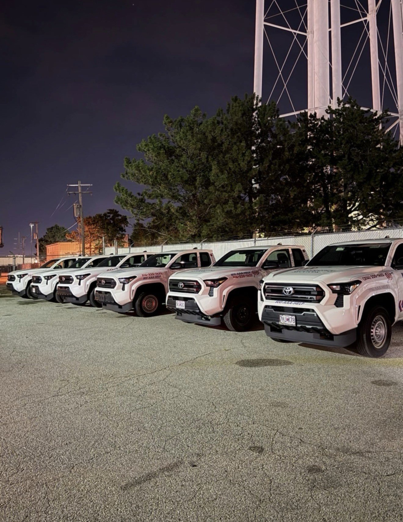 Row of Johnathan's Towing AAA roadside assistance trucks at night