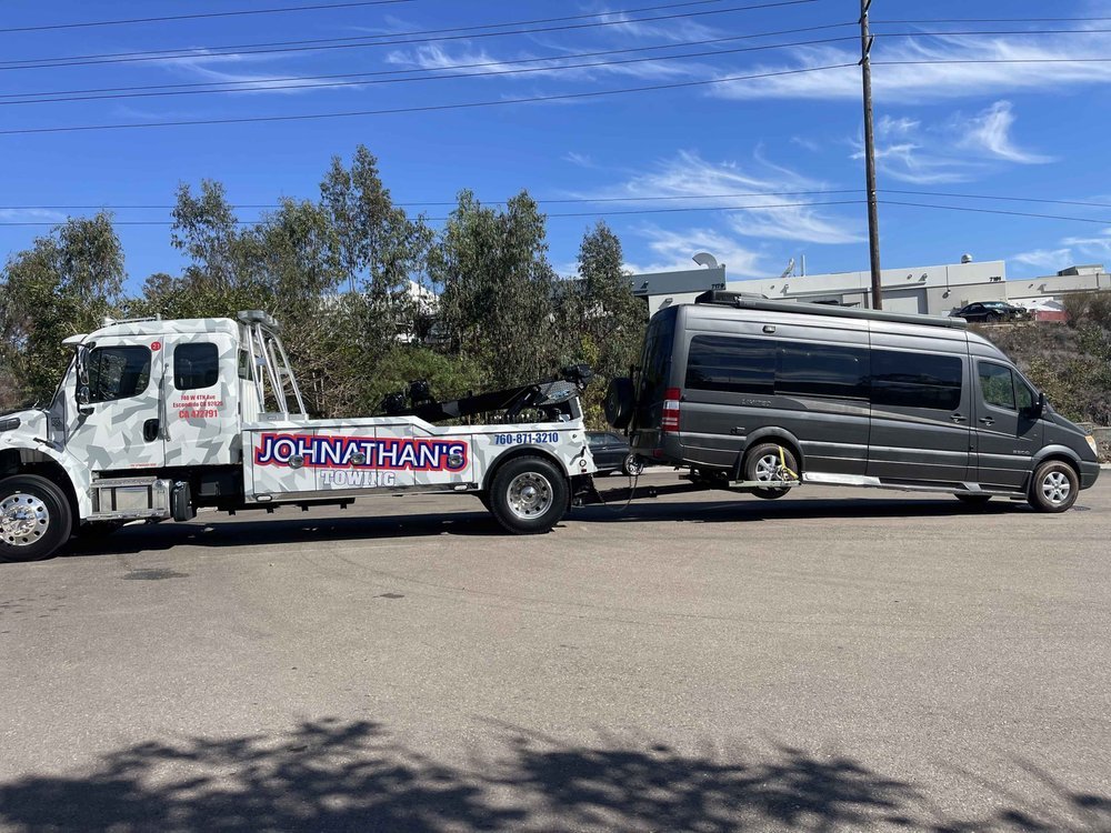 Heavy-duty tow truck with long equipment trailer under an overpass